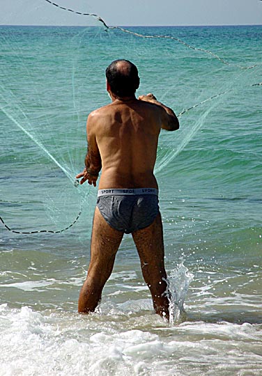 דייג פורש מכמורת בחוף הים מצפון להרצליה, שביל ישראל 2003