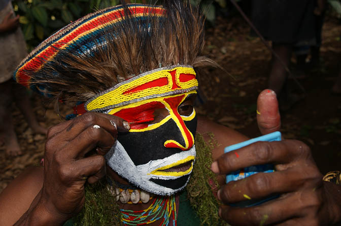 A young Kopi man applying makeup on his face for a Polga Singsing, in the Western Highland Province 2009
