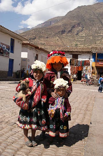 Three girls in traditional colorful clothes in the central plaza, Pisac 2008