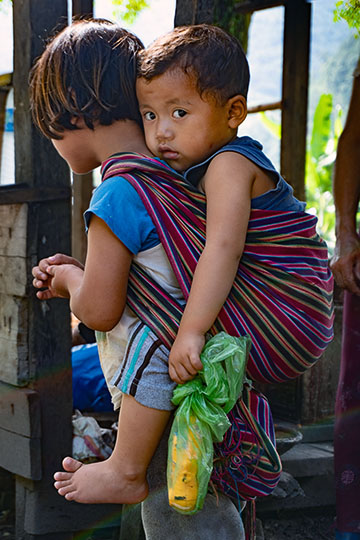 A girl carrying her younger brother on her back, central Bhutan 2018