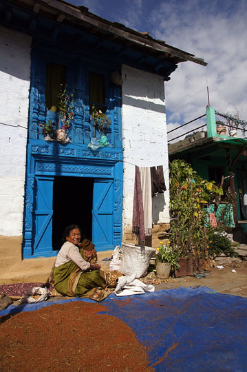 A woman in front of her house extracts beans from pods and dries amaranth seeds, Pangu 2011
