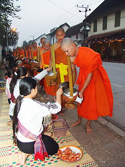 Local women giving alms to the monks very early in the morning, in a Buddhist regimented ritual of 'making merit’, Luang Prabang 2007