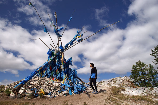 A local walks clockwise around an Ovoo, constructed of rocks, wood and Khatak (silk scarves), Khatgal, North Mongolia 2010