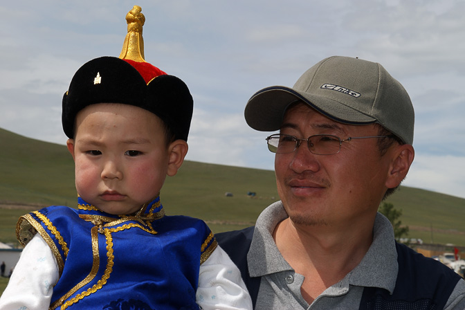 Boy in a festive costume and his father viewing the Naadam games, Tsetserleg 2010