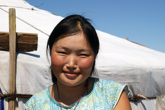 A smiling young girl by her family Ger (Mongolian home tent) close to Darkhan, Central Mongolia 2010