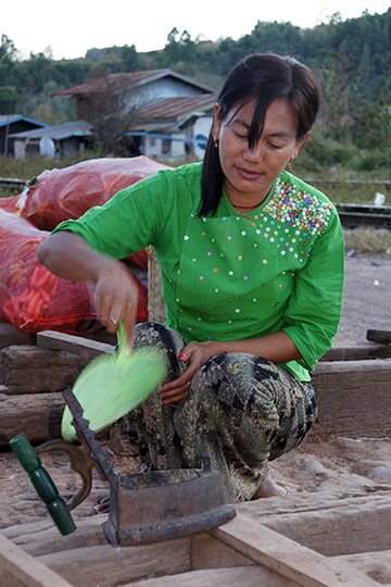 A woman lighting the coals in a charcoal iron in the train station, Kalaw to Inle Lake trek 2015