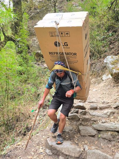 A porter carrying a refrigerator up the Langtang trail, 2025