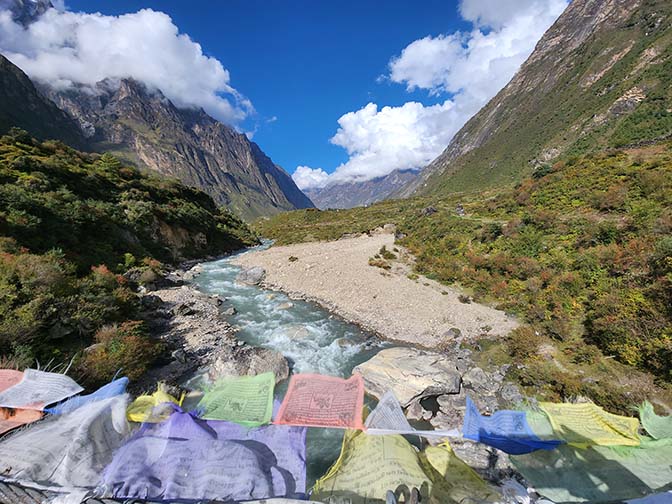 Prayer flags flutter in the wind from a suspension bridge over Tsum River, 2022