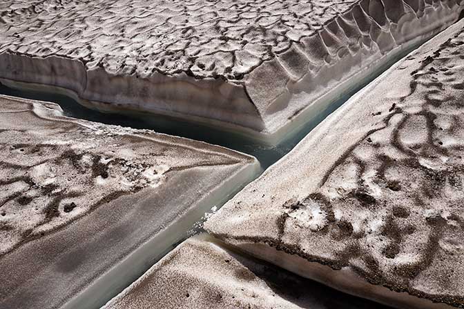 Ash on the melting ice in the lake at the bottom of Mutnovsky Volcano's caldera, 2016