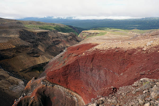 Red lava walls at the deep canyon created by the river that drains the caldera of Mutnovsky Volcano, 2016