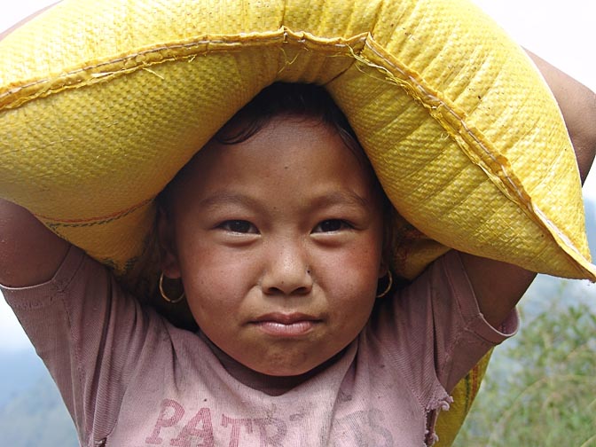 ילדה נפאלית סוחבת שק אורז על ראשה, בדרך בין קנג'ה לסטה, בטרק הקומבו לאוורסט, נפאל 2004