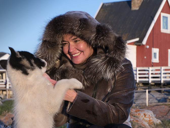 Paarna, an Inuit woman, frolicking with a puppy in Ilimanaq, 2017