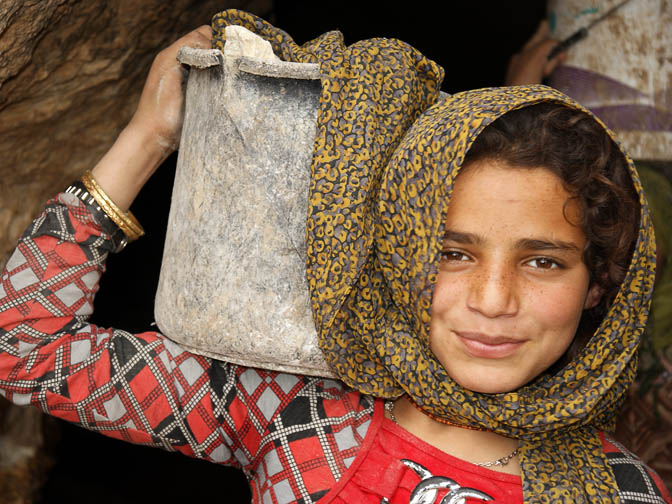 Hiba, a Palestinian farmer, carrying a bucket at the entrance to a cave of residence, Al-Mufaqara 2011