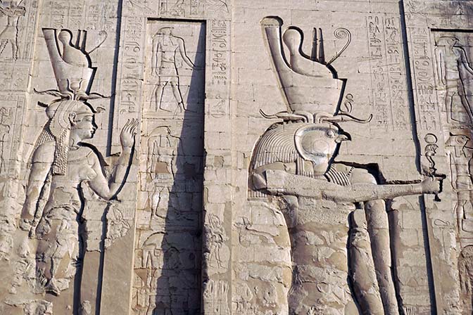 The huge bas-reliefs of god Horus, falcon headed, and his wife goddess Hathor, decorate the north wall of the Temple at Edfu, 2017