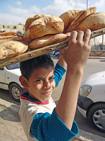 ילד מקומי נושא מגש פיתות מהמאפיה בגיזה, קהיר 2006