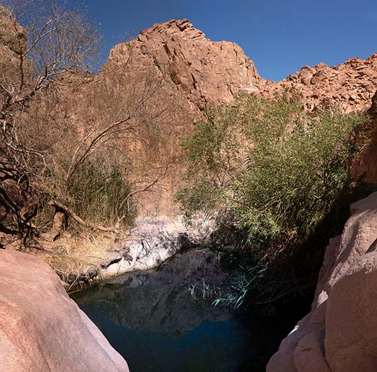 Galt el-Azraq granite pool under massive boulders and surrounded by lush vegetation, in Wadi Talaa Kibira, 2021