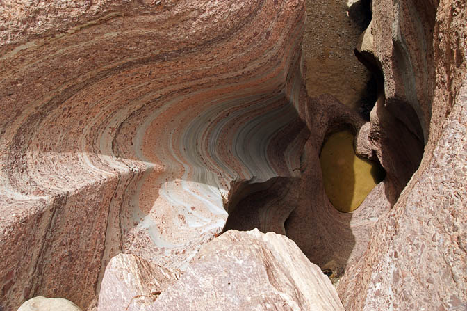 A water pit down the colored perpendicular walls of Wadi Tajra, 2010