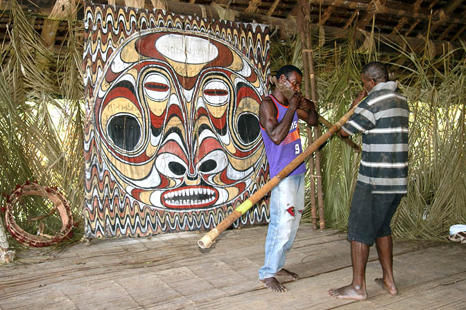 Yugin and friend play the bamboo flute inside a Haus Tambaran (Spirit House) in Kanganaman, the Sepik River 2009 