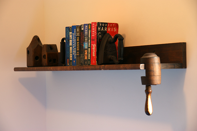 מדף ספרים בחדר שינה של יעקב, עם מגהצים ישנים התומכים בספרים ופריטי עץ מיוחדים, 2009